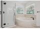 Bright bathroom featuring a glass-enclosed shower and large soaking tub under window at 3701 Bounty Ct, Matthews, NC 28104