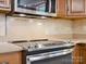 Modern stainless steel stove with glass cooktop and backsplash with wood cabinets above at 3701 Bounty Ct, Matthews, NC 28104
