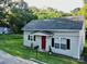 Exterior view of a cozy home featuring a gray roof, red door, and a well-maintained lawn at 409 W Norment Ave, Gastonia, NC 28052