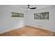 This bedroom features hardwood floors, a modern ceiling fan, and two windows with a view of the surrounding trees at 4209 Windwood Cir, Charlotte, NC 28226