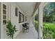 A covered porch with two black chairs, white brick wall, and black framed windows at 4209 Windwood Cir, Charlotte, NC 28226
