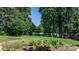 Grassy backyard featuring a landscaped flower bed, and a rustic stone bench, surrounded by mature trees at 4278 Harbor Ln, Sherrills Ford, NC 28673