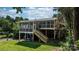 Backyard featuring a lush lawn, mature trees, and a screened-in porch with stairs attached to the home at 4278 Harbor Ln, Sherrills Ford, NC 28673