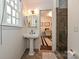 Cozy half bathroom with charming pedestal sink and a view to the office at 5301 Addison Dr, Charlotte, NC 28211