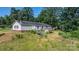 Home with wooden deck and outbuilding set amongst mature trees on a private, overgrown lot at 6314 Providence Church Rd, Vale, NC 28168