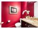 Stylish powder room with red walls, granite countertop, and decorative mirror at 7327 Snowbird Ct, Mint Hill, NC 28227