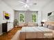 Staged bedroom featuring a queen bed, two windows, and hardwood flooring at 8701 Holly Creek Ct, Charlotte, NC 28216