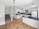 Bright kitchen with white cabinetry, black counters, wood floors, and stainless steel appliances, alongside access to stairs at 9121 Charminster Ct, Charlotte, NC 28269