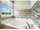 Close-up of a luxurious bathtub with tile backsplash and a view of the outdoors at 1006 Spring Rose Ln, Matthews, NC 28104