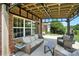 Comfortable outdoor patio featuring wicker furniture, a brick exterior, and an attached wooden roof structure at 1006 Spring Rose Ln, Matthews, NC 28104