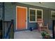 Inviting front porch featuring a cozy rocking chair, an orange front door, and black railings at 108 Graham St, Stanley, NC 28164