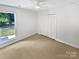 Bright bedroom features a ceiling fan, carpet flooring, and a closet with folding doors at 10934 Coachman Cir, Charlotte, NC 28277