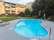 Community swimming pool with lounge chairs surrounded by mature landscaping and building at 1323 Queens Rd # 327, Charlotte, NC 28207