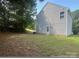 Exterior side-view showing the siding, grassy lot, and trees in the backyard of the property at 165 Brantley Place Dr, Mooresville, NC 28117