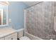 Cozy bathroom with light blue walls, white vanity, toilet, and tub with leaf-patterned shower curtain at 1655 Woodhaven Rd, Rock Hill, SC 29732