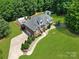 Aerial view of brick home with a large yard, in-ground pool, driveway, landscaping, and an outbuilding at 1842 Caroline Way, Fort Mill, SC 29715