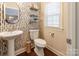 Stylish half bath features decorative wallpaper, floating shelves, pedestal sink, and wood-look flooring at 4203 Flint Dr, Lancaster, SC 29720