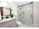 Bathroom with a tiled shower, glass door, modern vanity, and a sleek black faucet at 4219 Tipperary Pl, Charlotte, NC 28215