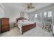 Bright bedroom featuring a ceiling fan, plantation shutters, neutral carpet, and a wood-trimmed bed at 44424 Oriole Dr # 200, Indian Land, SC 29707