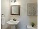 Powder room featuring a pedestal sink, framed mirror, neutral paint, and decorative artwork at 901 Deercross Ln, Waxhaw, NC 28173