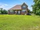 Spacious backyard showcasing the beautiful brick home, lush lawn and scenic landscape at 1011 Duntov Dr, Monroe, NC 28110