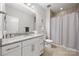 Well-lit bathroom with a granite countertop vanity, toilet, and shower-tub combo with curtain at 12415 Es Draper Dr, Huntersville, NC 28078