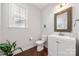 Well-lit half bathroom featuring dark hardwood floors, a white vanity, decorative mirror, and neutral paint at 12415 Es Draper Dr, Huntersville, NC 28078