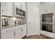 Close-up of the kitchen featuring white cabinets, stainless steel microwave and double ovens, and granite countertops at 12415 Es Draper Dr, Huntersville, NC 28078