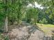 Long gravel driveway leading to a secluded property surrounded by lush green trees at 14019 Fountain Ln, Charlotte, NC 28278