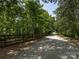 Private gravel driveway with wooden fence borders leading to a wooded property at 14019 Fountain Ln, Charlotte, NC 28278