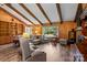 Comfortable living room with wood paneled walls, beamed ceiling, large windows, and a classic rocking chair at 143 Bostian Lake Rd, Statesville, NC 28677