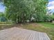 Backyard featuring a wooden deck, a large green space, mature trees, and a fenced yard at 14520 Cardamon Ct, Charlotte, NC 28273