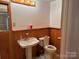 Bathroom with vanity sink, toilet and wooden paneling at 180 Tower Rd, Troy, NC 27371