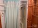 Bathroom including a modern shower with a light blue lace curtain, and wooden cabinets at 180 Tower Rd, Troy, NC 27371