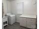 Well-lit laundry room with storage cabinets, sink, and modern washing machine at 180 Tower Rd, Troy, NC 27371