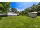 A spacious backyard featuring green grass, trees, shed, and a single-story home in the distance at 2488 Catawba Church Rd, Rock Hill, SC 29730