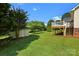Green backyard with a shed, wooden deck and stairs, backed by treeline; perfect for outdoor enjoyment at 2906 Plantation Way, Albemarle, NC 28001
