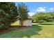 Exterior view of small storage shed on grassy lawn surrounded by mature trees under a sunny sky at 2906 Plantation Way, Albemarle, NC 28001
