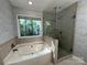 Well lit bathroom featuring a shower, soaking tub, and large window with wooded views at 5024 Ardenwoods Dr, Charlotte, NC 28215