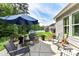 Backyard patio with shade umbrella, rocking chairs, and a view of the grassy lawn and treeline at 5129 Devonshire Rd, Denver, NC 28037