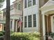 Brick townhouse featuring a charming balcony, covered porch, an American flag, and manicured landscaping at 570 Sixth Baxter Xing # 16, Fort Mill, SC 29708