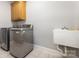 Well-lit laundry room with two large washing machines and a utility sink at 6612 Saunton Ct, Charlotte, NC 28277
