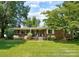 Charming single-story brick home with a well-maintained lawn, mature trees, and a welcoming front porch at 1104 Pump Station Rd, Kannapolis, NC 28081