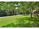 Expansive front yard with lush lawn, mature trees, and a glimpse of the charming home in the background at 1104 Pump Station Rd, Kannapolis, NC 28081