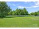 A beautiful, spacious, green back yard surrounded by a white wooden fence and trees at 142 Family Ln, Mount Holly, NC 28120