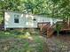Home's rear exterior features a wooden deck and neutral siding surrounded by mature trees at 16711 Indian Mound Rd, Albemarle, NC 28001