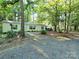 Secluded single story home nestled in a wooded lot with gravel driveway and a covered parking area at 16711 Indian Mound Rd, Albemarle, NC 28001