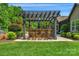 Outdoor bar area with stone facade, pergola, barstool seating, and lush green landscaping at 2009 Freeport Dr, Indian Trail, NC 28079
