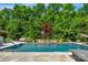 Backyard swimming pool with a small stone waterfall feature, surrounded by lush greenery at 2009 Freeport Dr, Indian Trail, NC 28079