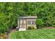 Backyard shed with double doors and a window, surrounded by mature trees and landscaping at 2009 Freeport Dr, Indian Trail, NC 28079